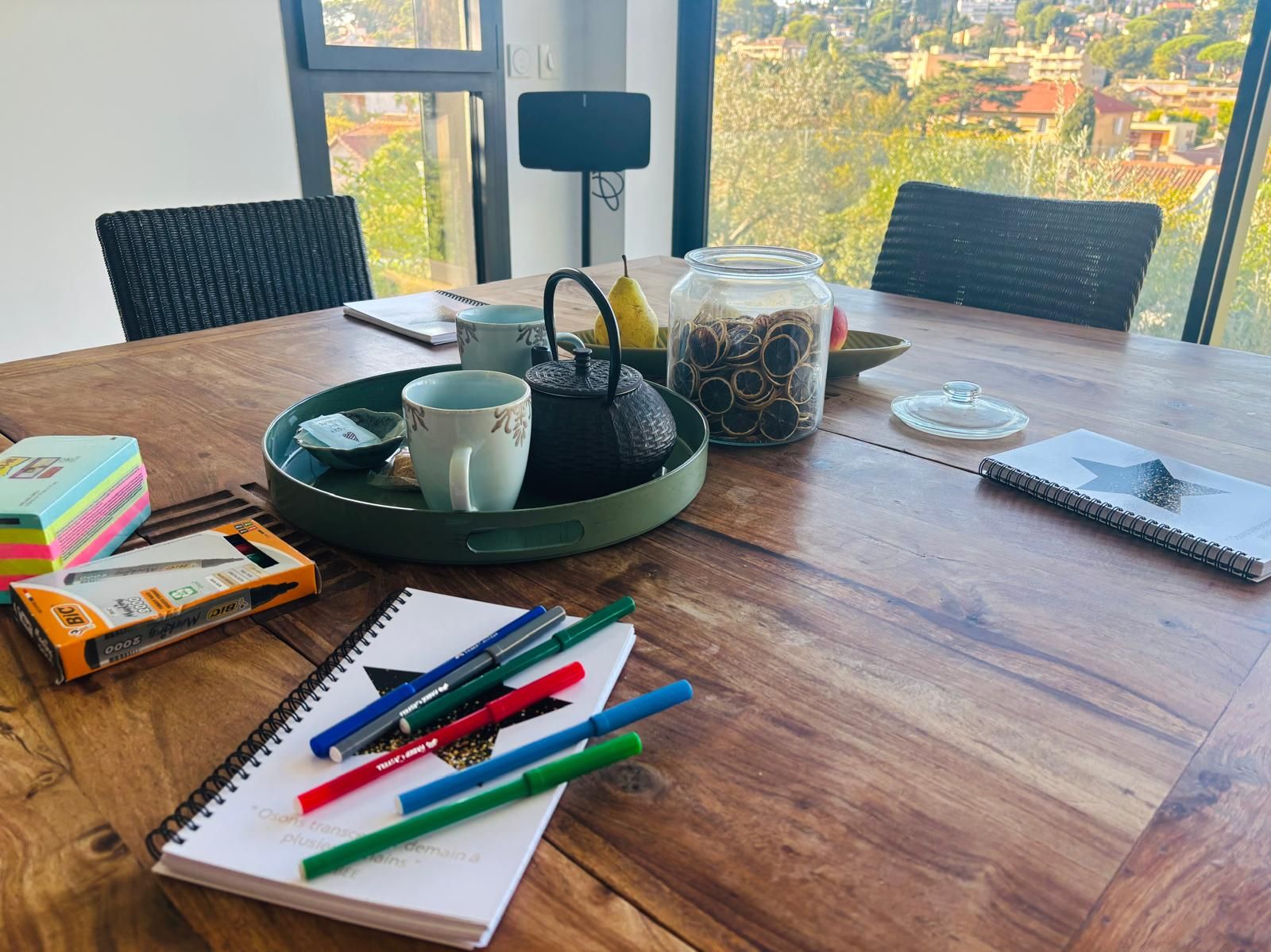 Table de travail du cabinet de Sanary-sur-Mer, devant une baie vitrée ouverte sur les collines